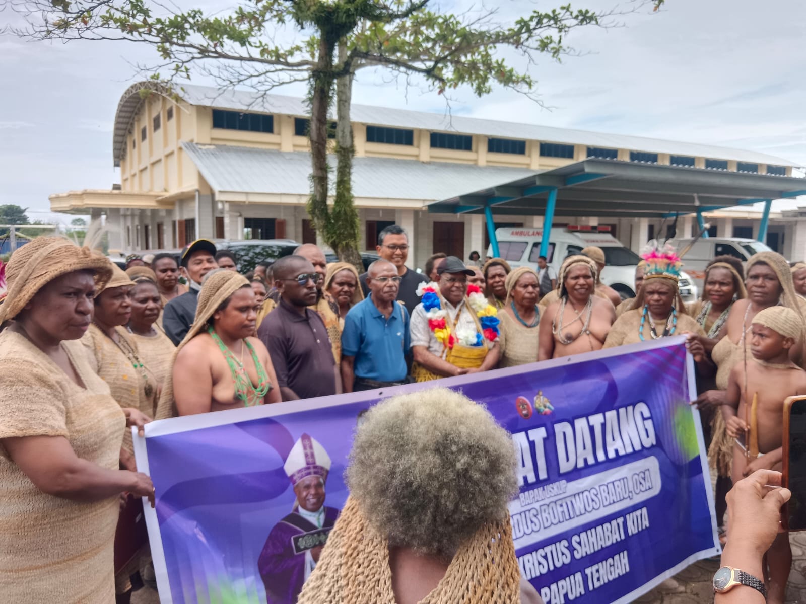 Uskup Timika Mgr. Bernardus Bofitwos Baru, OSA (memakai kalung bunga) saat tiba di Gereja Katolik Bukit Meriam dan disambut tari-tarian oleh mama-mama Papua Jumat, (20/3/2026). - Wagadei.id/Titus Ruban.